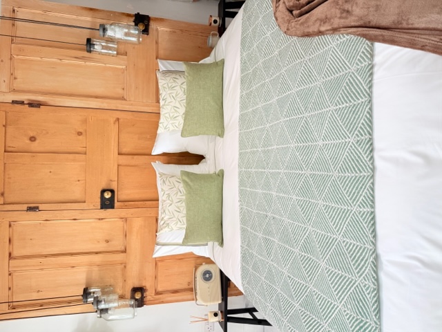 Doppelbett mit weisser Bettwäsche  und 3 grünen Streifen